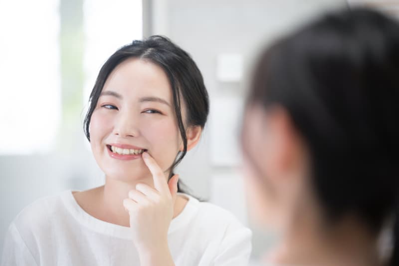 歯の矯正できれいになった歯並びを鏡で見る女性