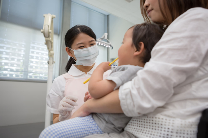 小さい子どもの保護者にも歯磨き方法について説明する歯科衛生士