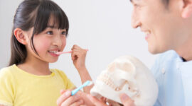 歯科医から歯磨き指導を受ける子ども