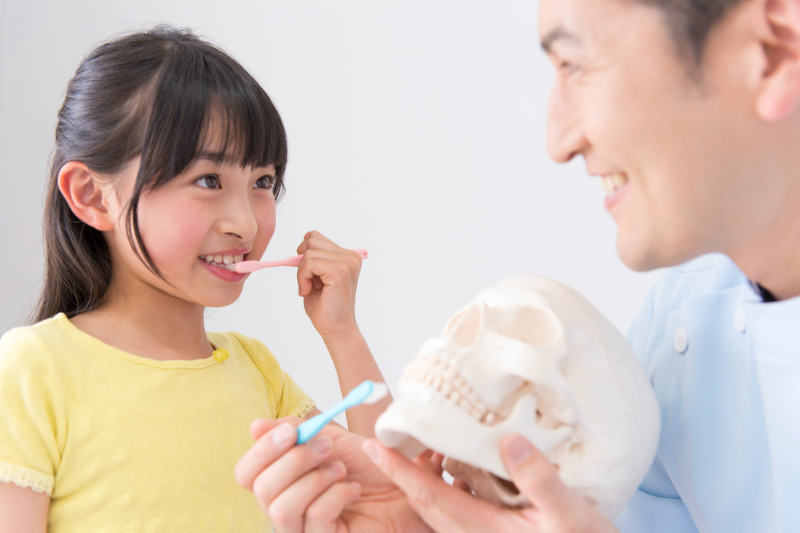 歯科医から歯磨き指導を受ける子ども