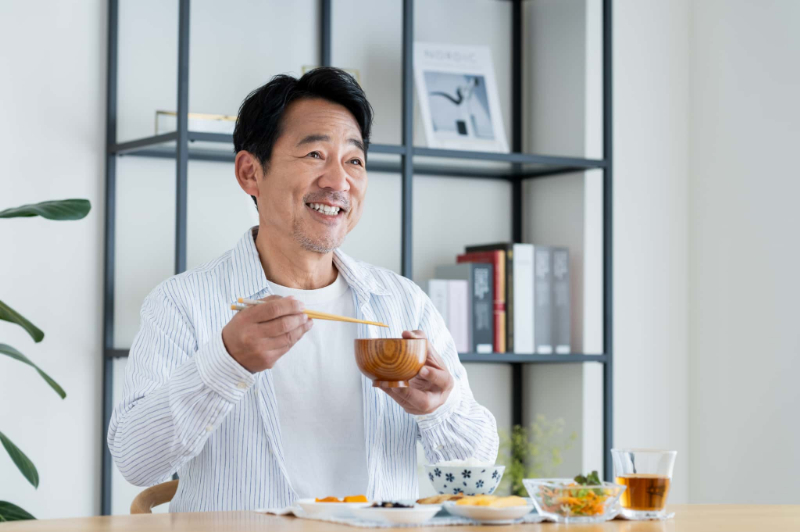 おいしくご飯を食べている禁煙して歯周病が改善した男性