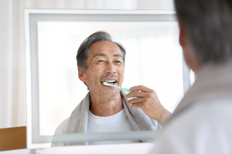 鏡を見ながらしっかり歯みがきをする喫煙者の男性