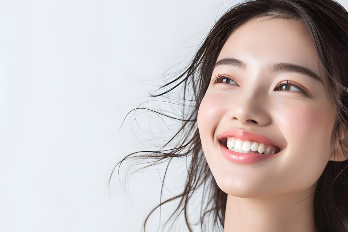 ホワイトニングで白くなった歯を見せて笑う女性