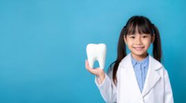 歯の模型を手にした白衣を着た子ども
